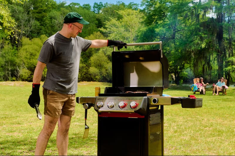 Man grilling outdoors with a group of people in the background