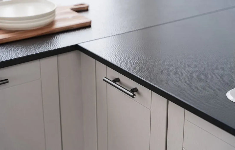 Kitchen cabinets with black countertop and wooden cutting board