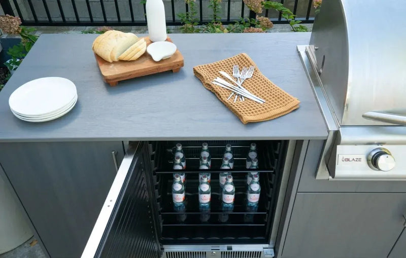 Outdoor kitchen setup with a refrigerator, cutting board, plates, and utensils.
