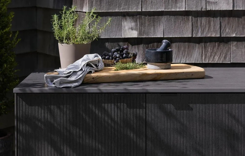Wooden cutting board with kitchen items on a black outdoor surface