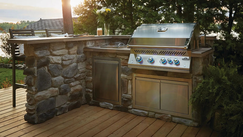 Outdoor kitchen with stone wall and gas grill on a wooden deck.