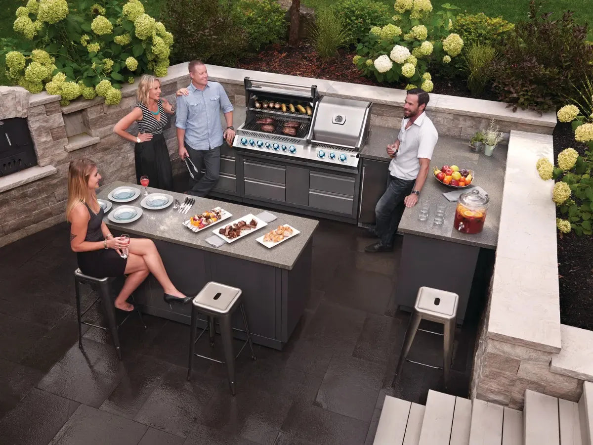 Outdoor kitchen with people around a grill and dining area.