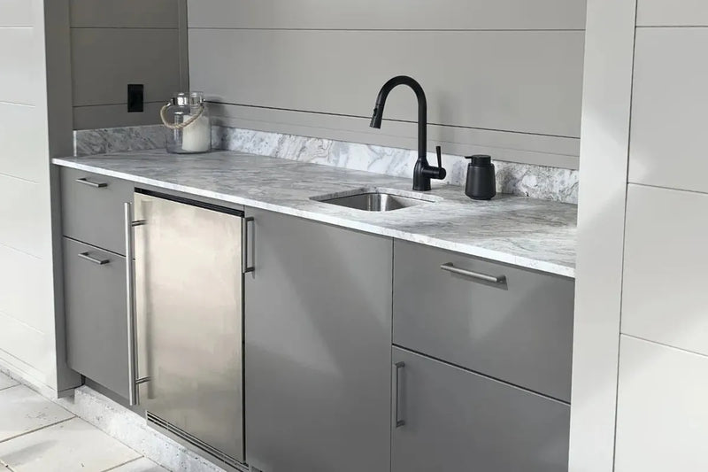 kitchen cabinetry featuring matte gray steel cabinets, a white marble countertop, a built-in stainless steel refrigerator, and a black gooseneck faucet.