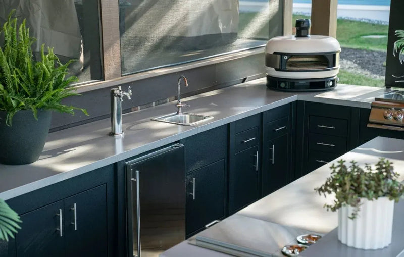 Modern kitchen with black cabinets, stainless steel appliances, and a view of a lake.
