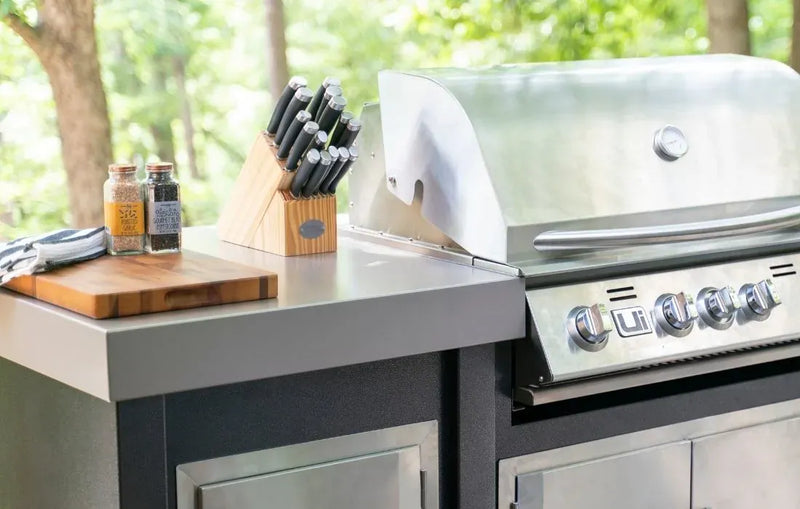 Outdoor kitchen setup with a grill, cutting board, and knife set.